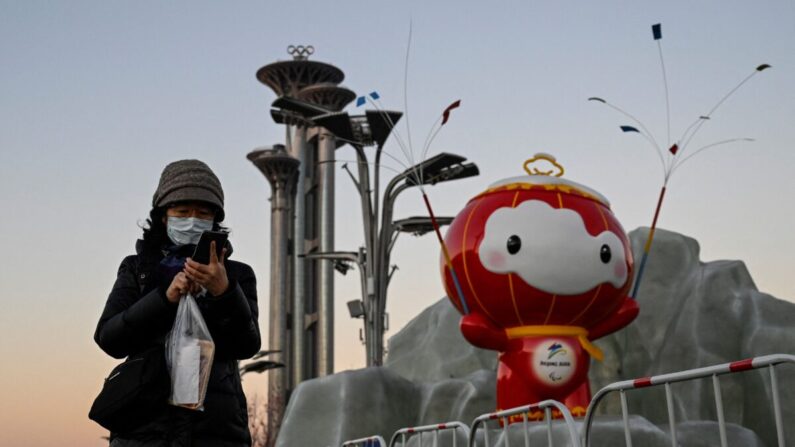 Una mujer comprueba su teléfono delante de una instalación de Shuey Rhon Rhon, la mascota de los Juegos Paralímpicos de Invierno de Beijing 2022, en el Parque Olímpico de Beijing, el 13 de enero de 2022. (Jade Gao/AFP vía Getty Images)