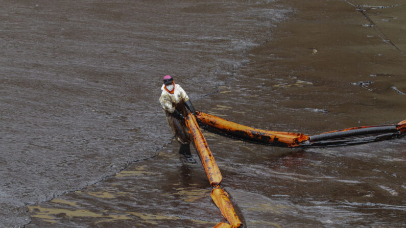 Un empleado de Repsol arrastra una barrera de contención durante la limpieza en la orilla de la playa de Cavero el 20 de enero de 2022 en Ventanilla, Perú. (Marcos Reategui/Getty Images)