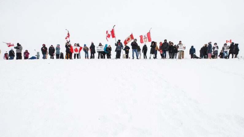 Los partidarios de un convoy de camioneros que conducen desde la Columbia Británica a Ottawa en protesta por el mandato de la vacuna COVID-19 para los camioneros transfronterizos se reúnen cerca de un paso elevado de la autopista en las afueras de Toronto, Ontario, Canadá, 27 de enero de 2022.(COLE BURSTON/AFP vía Getty Images)