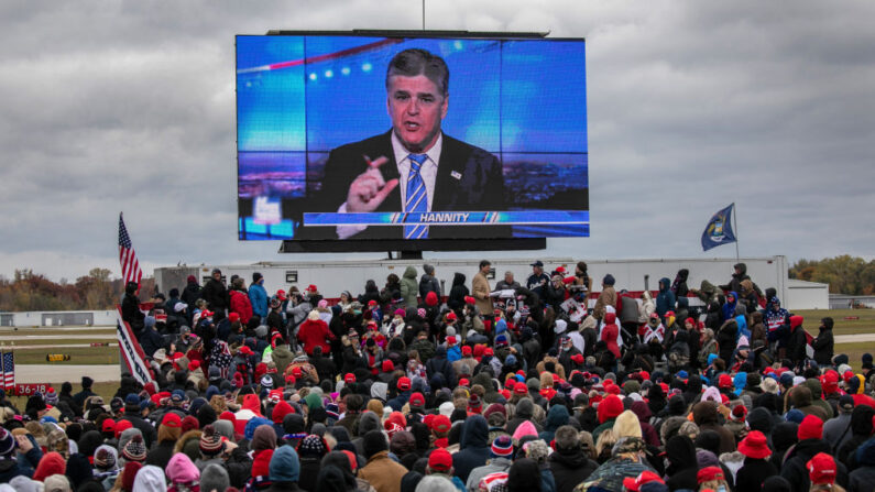 Partidarios del entonces presidente de Estados Unidos, Donald Trump, ven un video con el presentador de Fox, Sean Hannity, antes de la llegada de Trump a un mitin de campaña en el Aeropuerto Internacional del Condado de Oakland el 30 de octubre de 2020 en Waterford, Michigan. (John Moore / Getty Images)