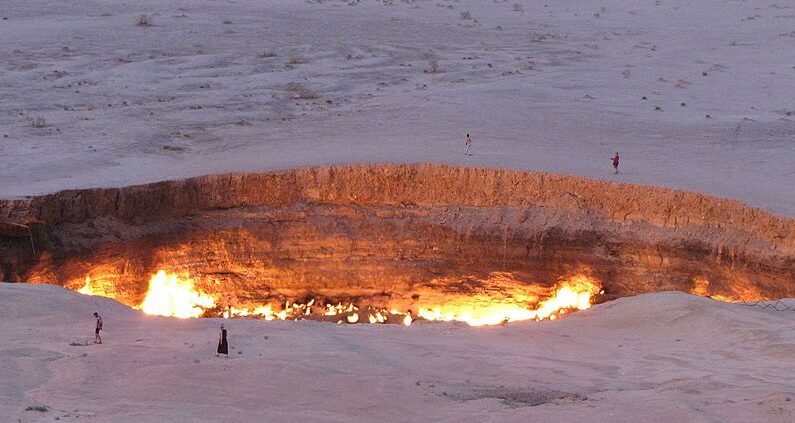 Una foto tomada el 3 de mayo de 2014 muestra a personas visitando la "Puerta del infierno", un enorme cráter de gas en llamas en el corazón del desierto de Karakum, en Turkmenistán. (IGOR SASIN/AFP via Getty Images)