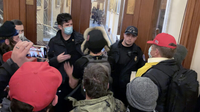 Christopher Ray Grider (a la derecha, con una bandera amarilla atada al cuello) justo antes de entregar un casco negro al alborotador Zachary Alam en el vestíbulo de la presidenta de la Cámara de Representantes el 6 de enero de 2021. (Vídeo/Sam Montoya para The Epoch Times)