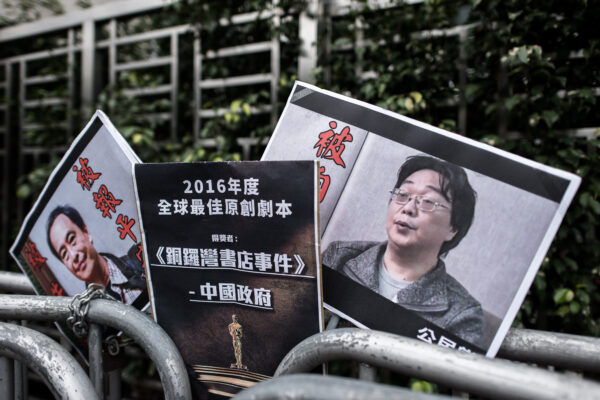 Carteles con la imagen del librero desaparecido Gui Minhai (der.) son dejados por miembros del Partido Cívico frente a la oficina de enlace con China, en Hong Kong, el 19 de enero de 2016. (Philippe Lopez/AFP vía Getty Images)