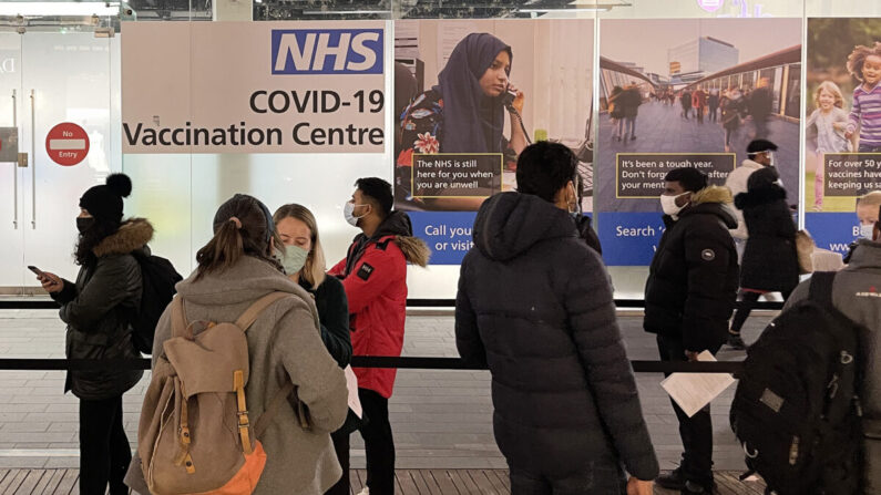 Una fila de personas esperando para recibir su vacuna de refuerzo contra el COVID-19 en un centro de vacunación del NHS en Londres el 14 de diciembre de 2021. (Leon Neal/Getty Images)