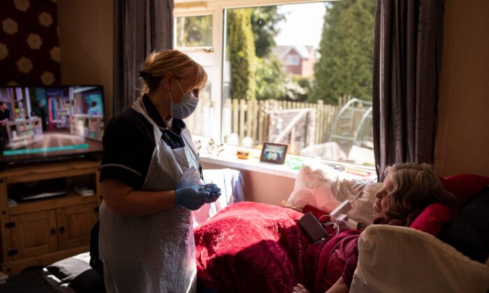 La jefa del equipo de vacunación de personas confinadas, Julie Fletcher, se prepara para administrar una dosis de la vacuna COVID-19 de AstraZeneca/Oxford a la paciente confinada en casa, Gillian Marriott, en su casa de Hasland, cerca de Chesterfield, en el centro de Inglaterra, el 14 de abril de 2021. (Oli Scarff/AFP vía Getty Images)