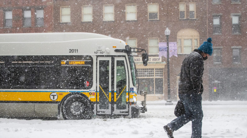 Un hombre camina junto a una parada de autobús en Harvard Square durante una tormenta de nieve en Somerville (Massachusetts) el 29 de enero de 2022. (Adam Glanzman/Getty Images)