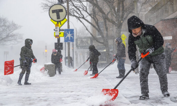 La gente limpia la acera junto a la parada de la MBTA de Harvard en Harvard Square durante una tormenta de nieve en Somerville, Massachusetts, el 29 de enero de 2022. (Adam Glanzman/Getty Images)