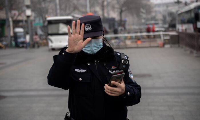 Un policía hace un gesto a un periodista para que no lo fotografíe en Beijing, China, el 5 de marzo de 2021. (NICOLAS ASFOURI/AFP vía Getty Images)