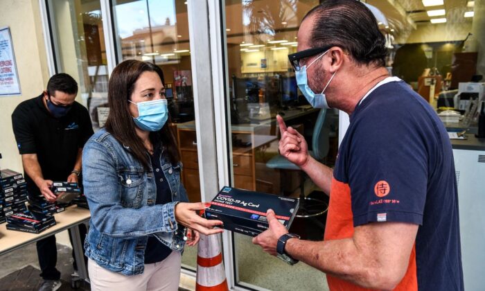 Empleados del Sistema de Bibliotecas Públicas de Miami-Dade distribuyen tests rápidos de autodiagnóstico COVID-19 en Miami (Florida) el 8 de enero de 2022. (Chandan Khanna/AFP vía Getty Images)