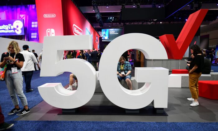 Usuarios de teléfonos celulares junto a una pantalla 5G de Verizon en la Electronic Entertainment Expo 2019, también conocida como E3, en Los Ángeles, California, el 12 de junio de 2019. (Frederic J. Brown/AFP/Getty Images)