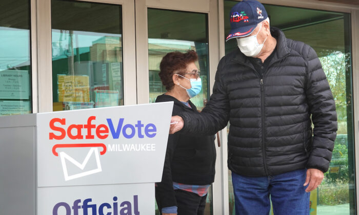 Unos residentes depositan votos por correo en una urna fuera de la biblioteca de la sucursal de Tippecanoe en Milwaukee (Wisconsin) el 20 de octubre de 2020. (Scott Olson/Getty Images)