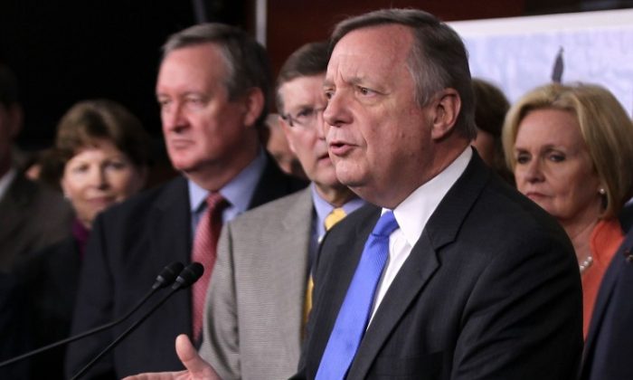 El líder de la bancada mayoría del Senado de EE. UU., el senador Richard Durbin (D-Ill.) habla como otros miembros del Congreso, incluyendo los senadores Jeanne Shaheen (D-N.H.) (Izq.), Mike Crapo (R-Idaho) (2do a la Izq.), Kent Conrad ( D-N.D.) (tercera izquierda) y Claire McCaskill (D-Mo.) (Der.) escuchan durante una conferencia de prensa en el Capitolio en Washington, el 16 de noviembre de 2011. (Alex Wong/Getty Images)