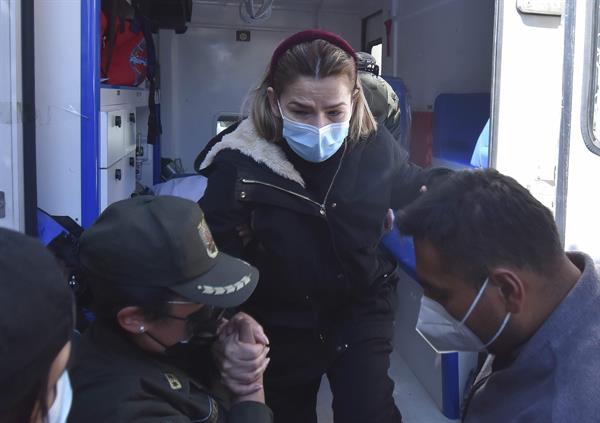 La expresidenta interina de Bolivia Jeanine Áñez (C) es asistida por una policía para bajar de una ambulancia que la llevó de vuelta a la cárcel en que está recluida, en La Paz (Bolivia), el 18 de agosto de 2021. EFE/Stringer
