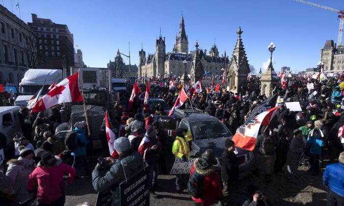 Manifestantes tras un camión protestan junto al Convoy de la Libertad contra las órdenes de vacunación y otras restricciones por COVID-19 ante el Parlamento en Ottawa el 29 de enero de 2022. (The Canadian Press/Adrian Wyld)