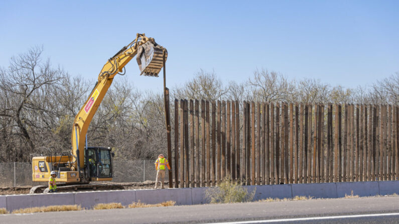 Trabajadores de la construcción colocan un bolardo a lo largo del muro fronterizo en Eagle Pass, Texas, el 25 de enero de 2022. (Charlotte Cuthbertson/The Epoch Times)