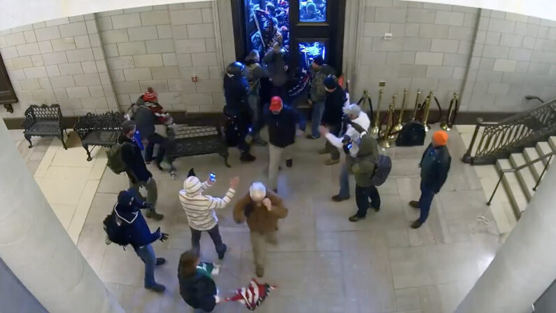 La gente entra en la Rotonda del Capitolio después de que un manifestante los deja entrar, en este video de vigilancia del 6 de enero de 2021. (Video Still/Departamento de Justicia de EE.UU.)
