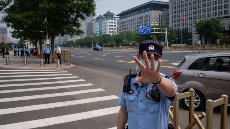 Un oficial de policía asegura un área y hace gestos antes de que pase un convoy de autobuses que transportan delegados antes de la ceremonia de apertura de la Conferencia Consultiva Política del Pueblo Chino (CCPPCh) en Beijing el 21 de mayo de 2020. (NICOLAS ASFOURI/AFP vía Getty Images)