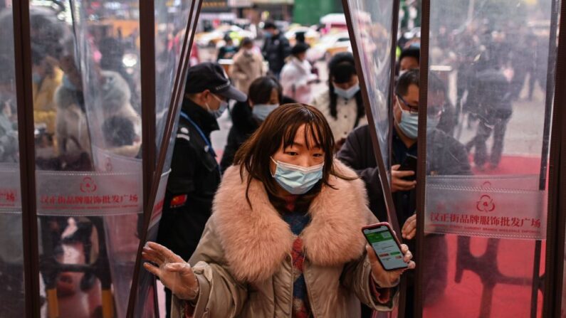 Una mujer con una mascarilla entra en un centro comercial después de mostrar su código sanitario en Wuhan, provincia central china de Hubei, el 22 de enero de 2021. (HECTOR RETAMAL/AFP vía Getty Images)