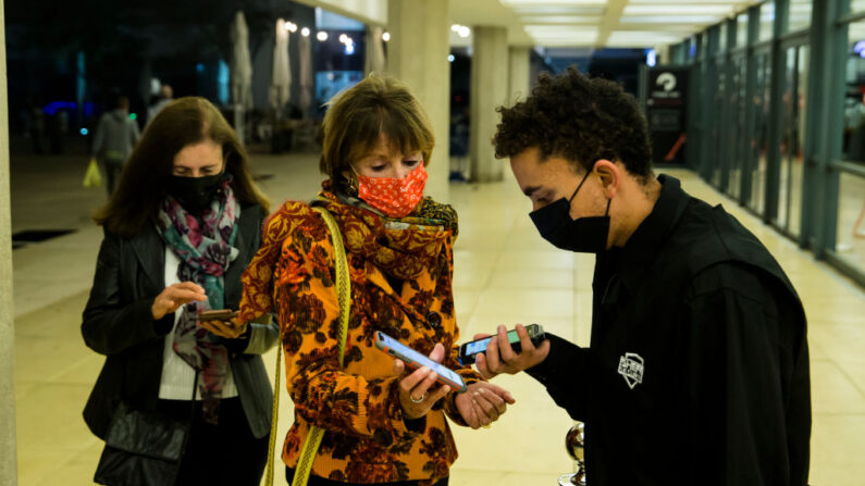 Mujeres israelíes presentan un certificado de vacunación "Covid19" denominado "Pase Verde", antes de entrar en una sala de conciertos de Tel Aviv el 17 de marzo de 2021 en Tel Aviv, Israel. (Amir Levy/Getty Images)