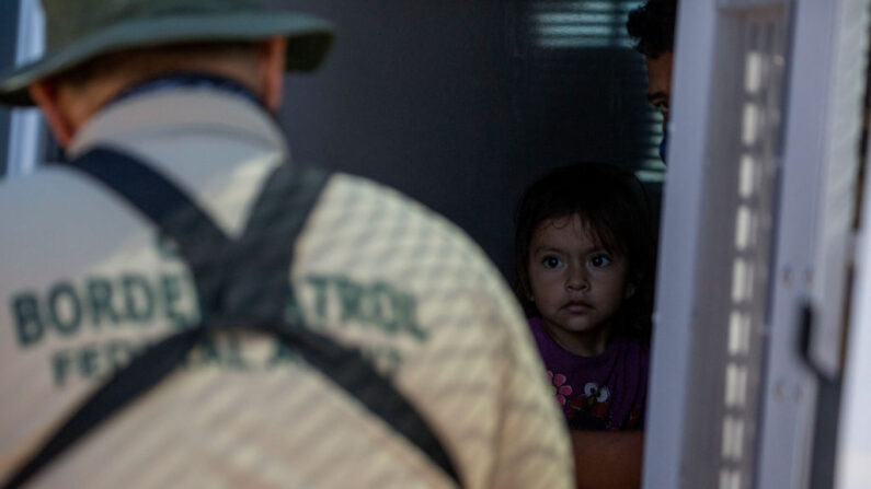 Una niña migrante de Guatemala mira desde el interior de una furgoneta mientras un agente de la Patrulla Fronteriza recaba información de sus padres después de que se entregaran a las autoridades en la frontera entre Estados Unidos y México el 12 de mayo de 2021 en Yuma, Arizona. (RINGO CHIU/AFP vía Getty Images)