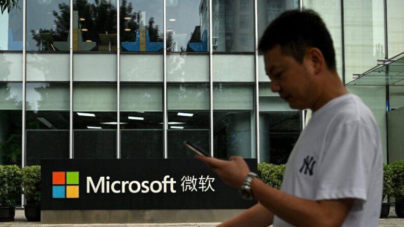 Un hombre utiliza su celular mientras camina frente a la sede local de Microsoft en Beijing el 20 de julio de 2021. (Noel Celis/AFP vía Getty Images)