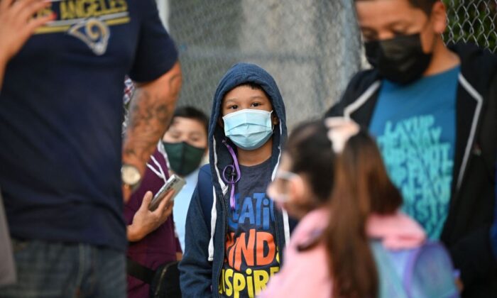 Estudiantes y padres con mascarillas esperan en fila el primer día del año escolar en la Escuela Primaria Grant, en Los Ángeles, California, el 16 de agosto de 2021. (Robyn Beck/AFP a través de Getty Images)