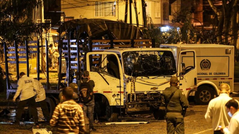 Personal de seguridad inspecciona un camión de la policía nacional destruido por un artefacto explosivo en Cali, Colombia, el 8 de enero de 2022. (PAOLA MAFLA/AFP vía Getty Images)