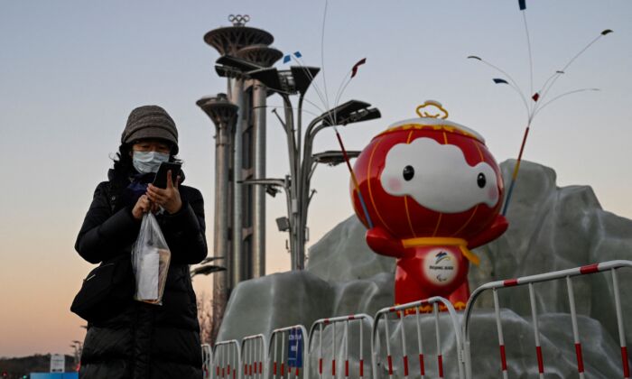 Una mujer revisa su teléfono frente a una instalación de Shuey Rhon Rhon, mascota de los Juegos Paralímpicos de Invierno de Beijing 2022 en el Parque Olímpico de Beijing, el 13 de enero de 2022. (Jade Gao/AFP a través de Getty Images)