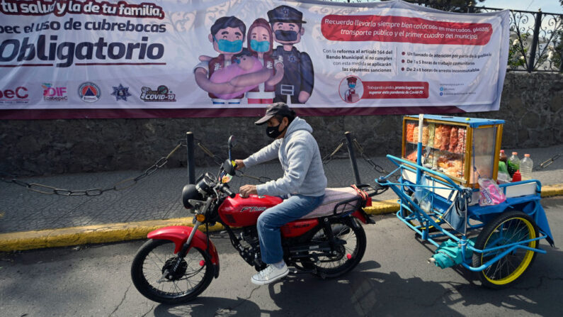 Un hombre con mascarilla  pasa junto a una valla que alerta del uso obligatorio de mascarillas en Ecatepec, México, el 24 de enero de 2022. (ALFREDO ESTRELLA/AFP vía Getty Images)