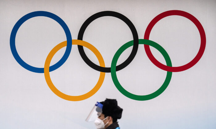 Un agente de seguridad con una mascarilla y una visera protectora de plástico pasa junto a los anillos olímpicos en el Centro Acuático Nacional de Beijing el 30 de enero de 2022. (Carl Court/Getty Images)