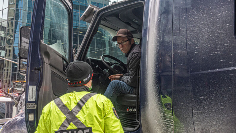  Un agente de policía habla con un camionero que bloquea la calle el 31 de enero de 2022 en Ottawa, Canadá. Miles de personas se manifestaron durante el fin de semana en apoyo de los camioneros que utilizaron sus vehículos para bloquear el acceso al Parlamento, la mayor parte del centro de Ottawa y la frontera con Alberta, con la esperanza de presionar al gobierno para que revierta la normativa de salud pública sobre COVID-19. (Alex Kent/Getty Images)