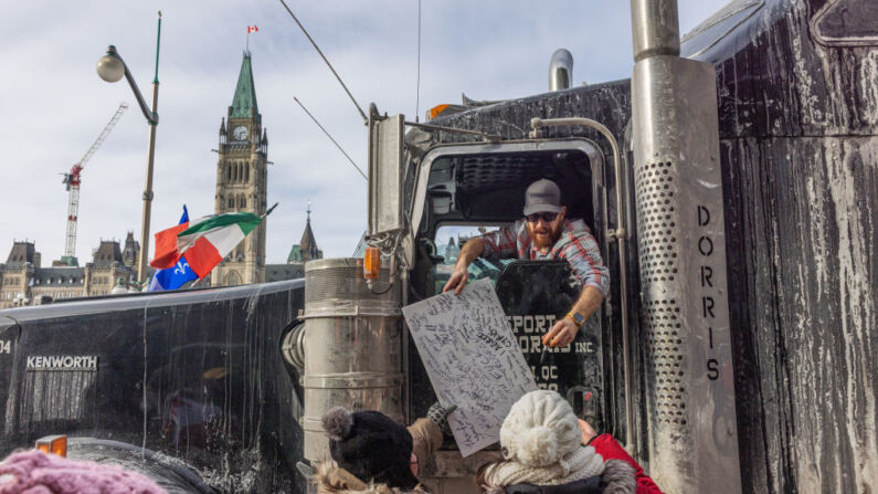Un camionero firma un cartel de protesta durante una manifestación contra las restricciones contra COVID-19 en la Colina del Parlamento el 30 de enero de 2022 en Ottawa, Canadá. Miles de personas se manifestaron durante el fin de semana en apoyo de los camioneros que utilizaron sus vehículos para bloquear el acceso al Parliament Hill, la mayor parte del centro de Ottawa y la frontera con Alberta, con la esperanza de presionar al gobierno para que revierta la normativa de salud pública COVID-19. (Foto de Alex Kent/Getty Images)