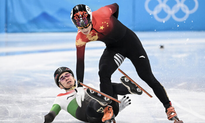 El húngaro Shaolin Sandor Liu (Izq.) cae junto al chino Ren Ziwei tras cruzar la línea de meta en la final A de la prueba masculina de patinaje de velocidad en pista corta durante los Juegos Olímpicos de Invierno de Beijing 2022 en el Estadio Cubierto de la Capital en Beijing el 7 de febrero de 2022. (Anne-Christine Poujoulat/AFP a través de Getty Images)