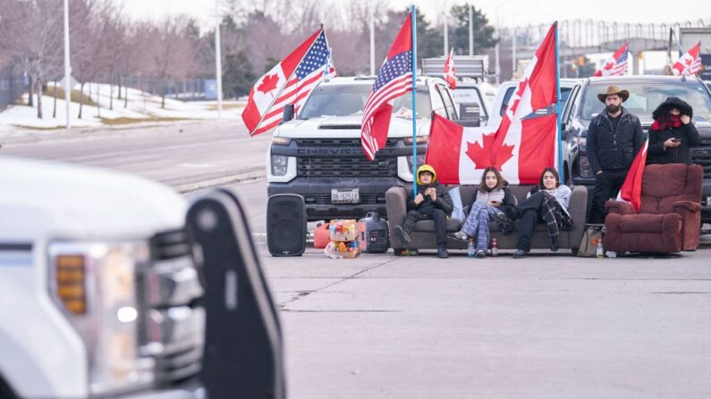 Manifestantes contra las órdenes de vacunación contra Covid-19 se sientan en un sofá mientras el grupo bloquea la carretera en el cruce fronterizo de Ambassador Bridge en Windsor, Ontario, Canadá, el 9 de febrero de 2022. (Geoff Robins/AFP a través de Getty Images)