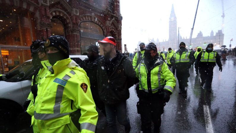 Oficiales de policía escoltan a un manifestante detenido hasta una patrulla durante una protesta por las normas sanitarias de la pandemia y el gobierno de Trudeau en Ottawa, Canadá, el 17 de febrero de 2022. (DAVE CHAN/AFP vía Getty Images)