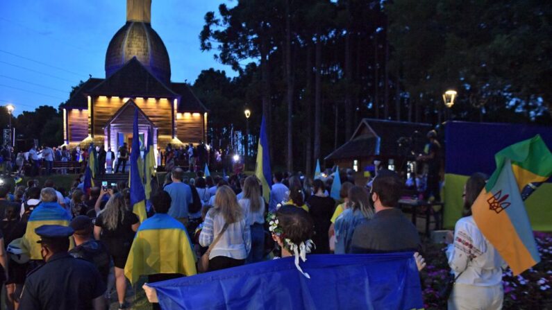 Miembros de la comunidad ucraniana con banderas nacionales, participan en una protesta contra la guerra y en apoyo a Ucrania en el Memorial Ucraniano en Curitiba, estado de Paraná, Brasil, el 25 de febrero de 2022. (NELSON ALMEIDA/AFP vía Getty Images)