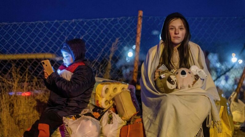 Helena (Der.) y su hermano Bodia (Izq.), de Lviv, permanecen en el paso fronterizo peatonal de Medyka, en el este de Polonia, el 26 de febrero de 2022, tras la invasión rusa a Ucrania. (WOJTEK RADWANSKI/AFP vía Getty Images)