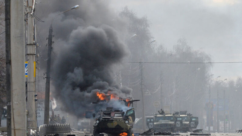TOPSHOT - Esta fotografía tomada el 27 de febrero de 2022 muestra un vehículo blindado de transporte de personal (APC) ruso ardiendo junto al cuerpo de un soldado no identificado durante los combates con las fuerzas armadas ucranianas en Kharkiv. (SERGEY BOBOK/AFP vía Getty Images)
