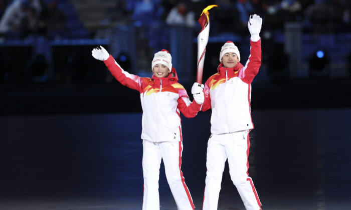 Los atletas chinos portadores de la antorcha Dinigeer Yilamujian y Zhao Jiawen sostienen la llama olímpica durante la ceremonia de apertura de los Juegos Olímpicos de Invierno de Beijing 2022 en el Estadio Nacional, el 4 de febrero de 2022 en Beijing, China. (Lintao Zhang/Getty Images)