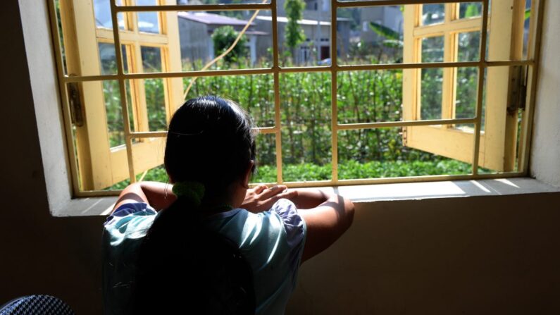 La niña de etnia h'mong Kiab (seudónimo para proteger su identidad) mira por una ventana en un centro para mujeres víctimas de la trata en la ciudad norteña de Lao Cai el 9 de mayo de 2014. Cuando Kiab cumplió 16 años, su hermano le prometió llevarla a una fiesta en una ciudad turística del norte de Vietnam. En cambio, la vendió a una familia china como novia. (Hoang Dinh Nam/AFP/Getty Images)