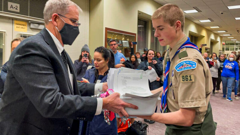 Jarod Missler, de 18 años, estudiante de último año de la Escuela Preparatoria Woodgrove, entrega una de las nueve cajas de declaraciones juradas notariadas al Jefe de Operaciones de las Escuelas Públicas del Condado de Loudoun (LCPS), Kevin Lewis, en el edificio administrativo de las LCPS en Ashburn, Virginia, el 8 de febrero de 2022. (Terri Wu/The Epoch Times)