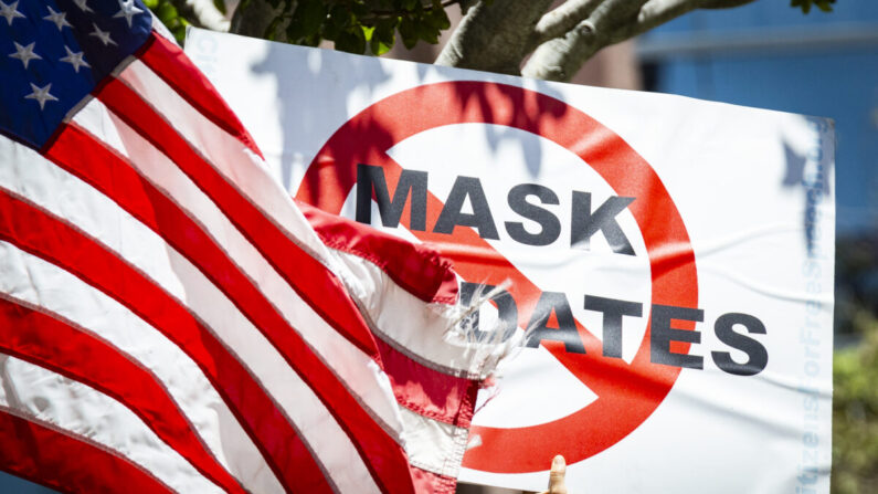 Un manifestante sostiene un cartel contra los mandatos de las en junio en Costa Mesa, California, el 10 de junio de 2021. (John Fredricks/The Epoch Times)