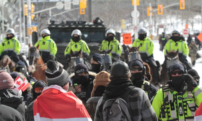Los manifestantes hacen frente a una línea policial respaldada por agentes montados en Ottawa el 18 de febrero de 2022. (Richard Moore/The Epoch Times)