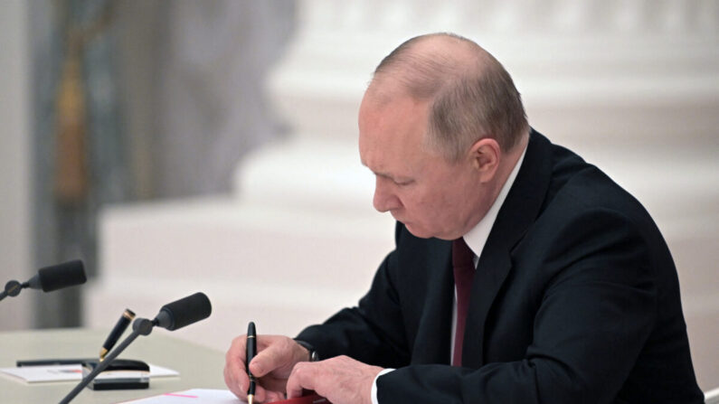 El presidente ruso Vladimir Putin firma documentos, incluyendo un decreto que reconoce como independientes a dos regiones separatistas respaldadas por Rusia en el este de Ucrania, durante una ceremonia en el Kremlin en Moscú el 21 de febrero de 2022. (Alexey Nikolsy/Sputnik/AFP vía Getty Images)