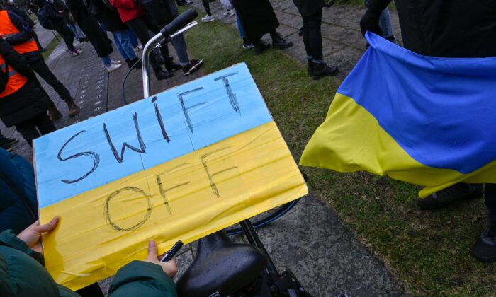 Un manifestante sostiene una pancarta con la leyenda "SWIFT OFF", en referencia al sistema de pagos interbancarios SWIFT, en Berlín, Alemania, el 25 de febrero de 2022. (John Macdougall/AFP vía Getty Images)