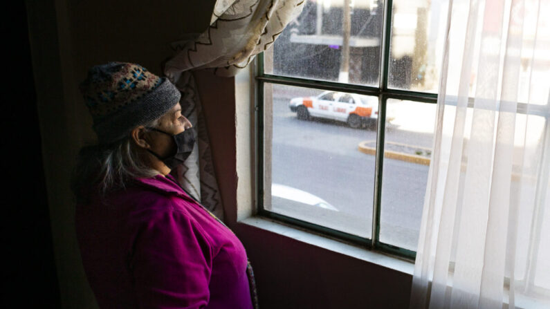 La trabajadora del ministerio Rosario Acuña Hernandez mira las calles de la Zona Norte desde la ventana de la Iglesia Cristiana Bethel en Tijuana, México, el 5 de febrero de 2022. (John Fredricks/The Epoch Times)