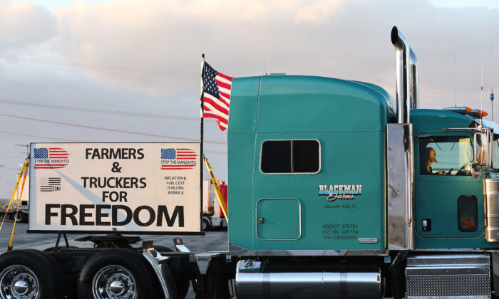 Un camionero en su cabina se reúne con simpatizantes un día antes de que un "Convoy del Pueblo" parta hacia Washington, DC, para protestar contra las órdenes de vacunación por COVID-19 en Adelanto, California, el 22 de febrero de 2022. (Mario Tama/Getty Images)