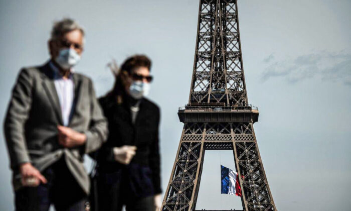 Un hombre y una mujer con mascarilla en Trocadero Plaza mientras una bandera nacional francesa ondea en la Torre Eiffel en París el 11 de mayo de 2020. (Philippe Lopez/AFP a través de Getty Images)
