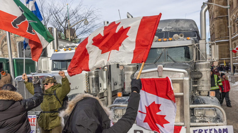 Una mujer agita una bandera y anima a los camioneros en protesta por los mandatos de la vacuna COVID-19 en Ottawa, Canadá, el 30 de enero de 2022. (Alex Kent/Getty Images)