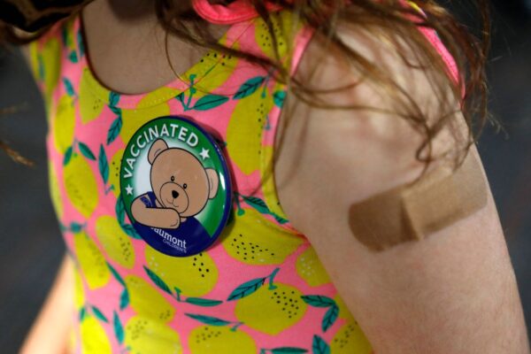 Una niña con un pin que recibió después de recibir su primera dosis de la vacuna contra la COVID-19 de Pfizer en las oficinas de Beaumont Health en Southfield (Michigan) el 5 de noviembre de 2021. (Jeff Kowalsky/AFP vía Getty Images)